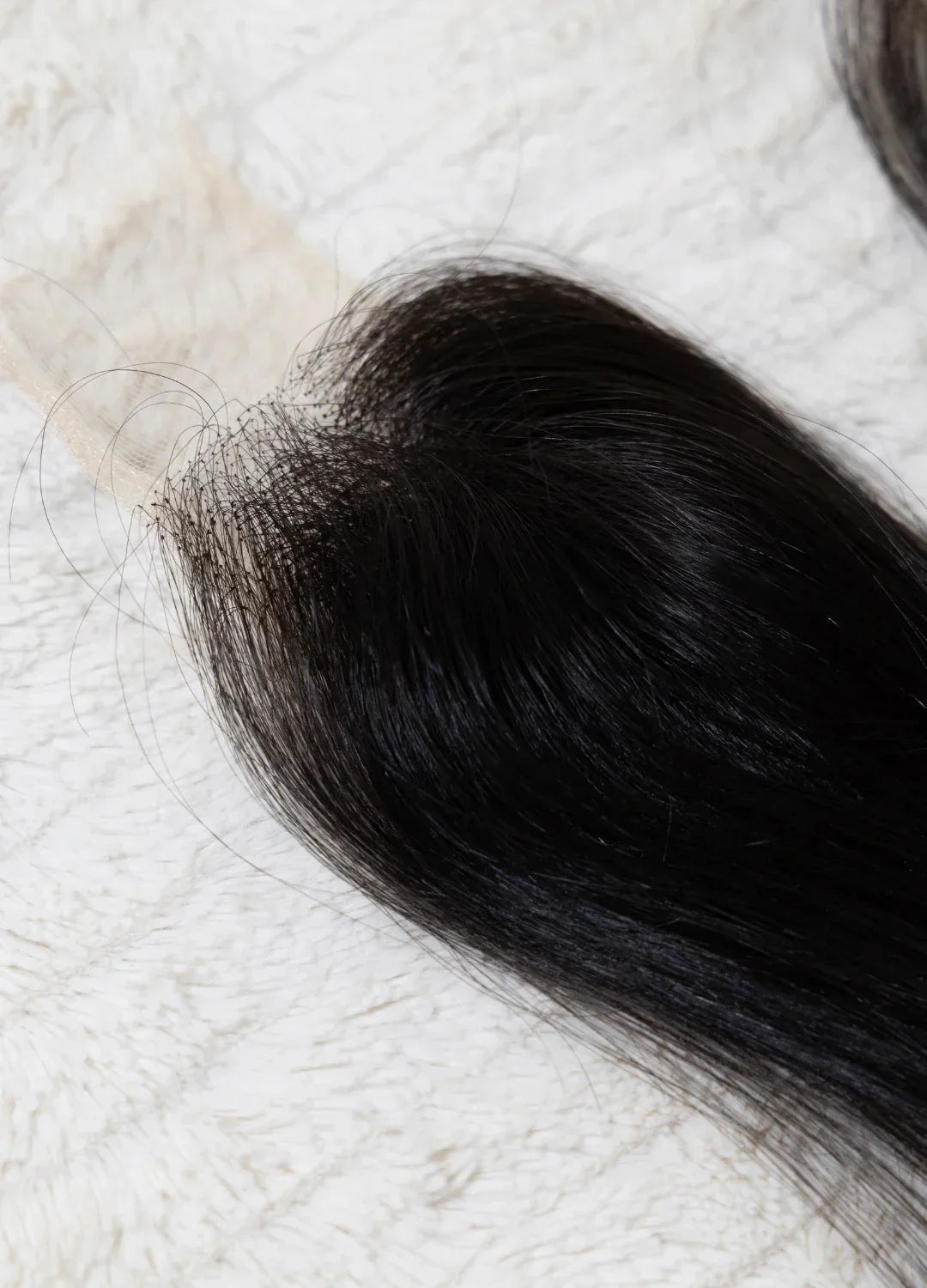 Extension ou perruque en cheveux noirs lisses sur fond clair texturé