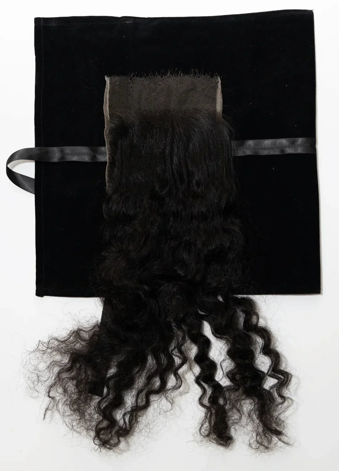 Extension de cheveux bouclés noirs naturels sur fond noir avec ruban satin